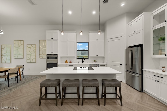 kitchen featuring stainless steel appliances, a kitchen island, glass insert cabinets, and decorative light fixtures