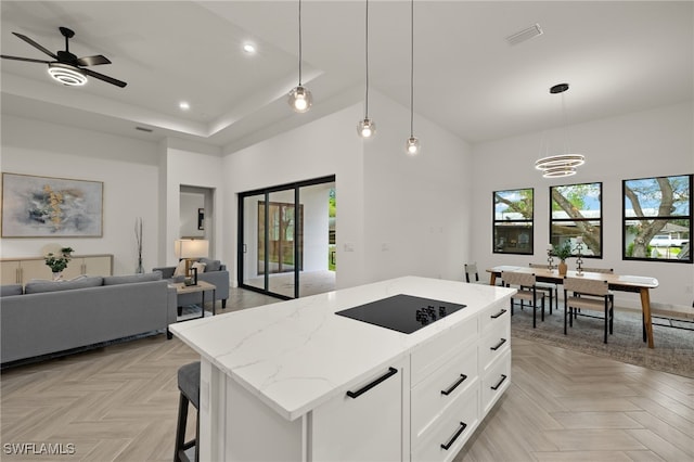 kitchen with pendant lighting, open floor plan, white cabinets, a kitchen island, and black electric cooktop