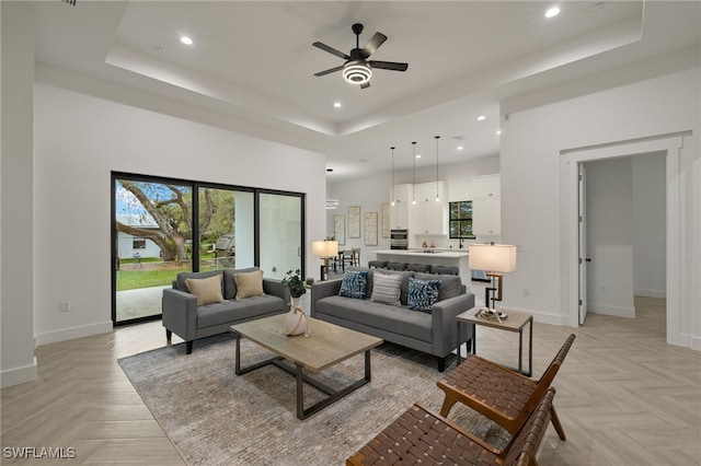 living room featuring a high ceiling, recessed lighting, a raised ceiling, and baseboards