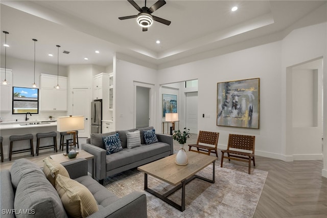 living area with recessed lighting, a raised ceiling, baseboards, and a high ceiling