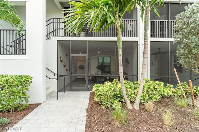 property entrance featuring a ceiling fan and stucco siding