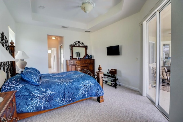 carpeted bedroom with ceiling fan, a raised ceiling, ensuite bath, and access to outside