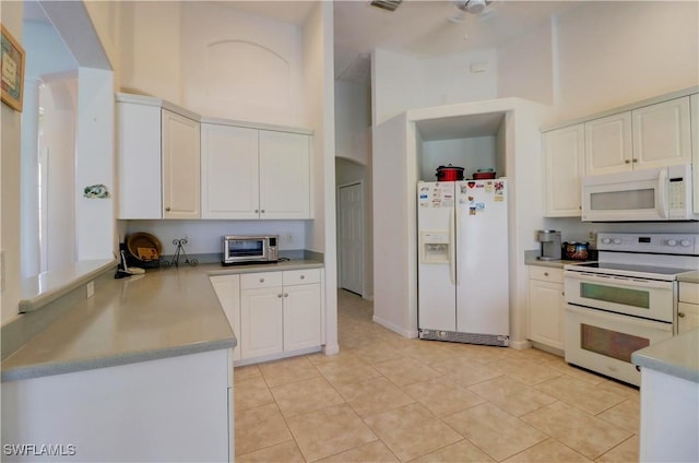 kitchen featuring white cabinetry, white appliances, light tile patterned flooring, and a towering ceiling