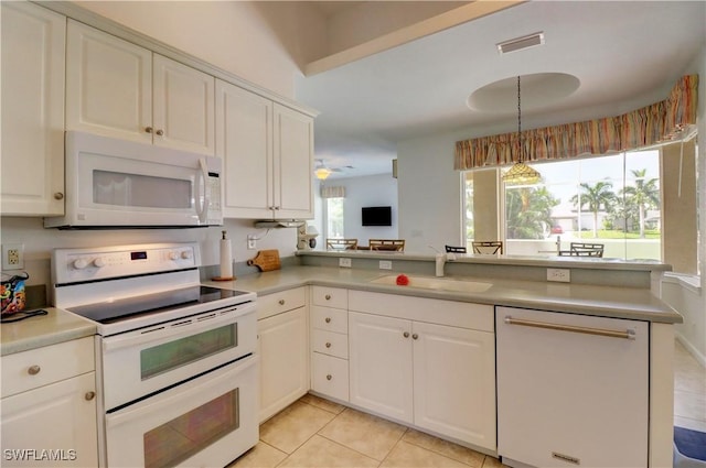 kitchen with white cabinetry, sink, light tile patterned floors, kitchen peninsula, and white appliances