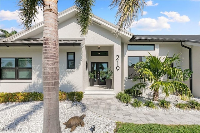 entrance to property featuring french doors and stucco siding