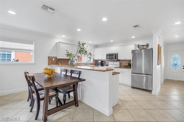 kitchen with a peninsula, visible vents, white cabinets, and stainless steel appliances