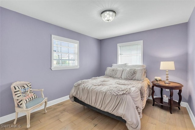 bedroom with light wood finished floors, multiple windows, and baseboards