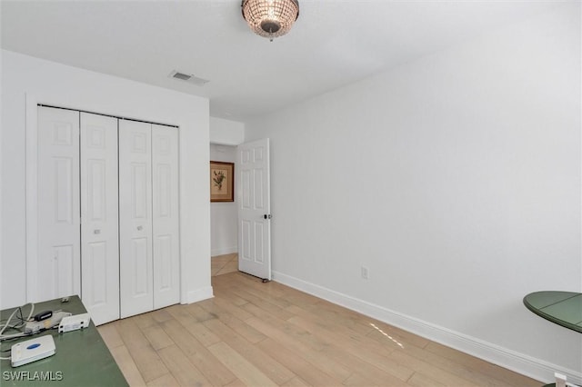 unfurnished bedroom with light wood-style flooring, a closet, visible vents, and baseboards