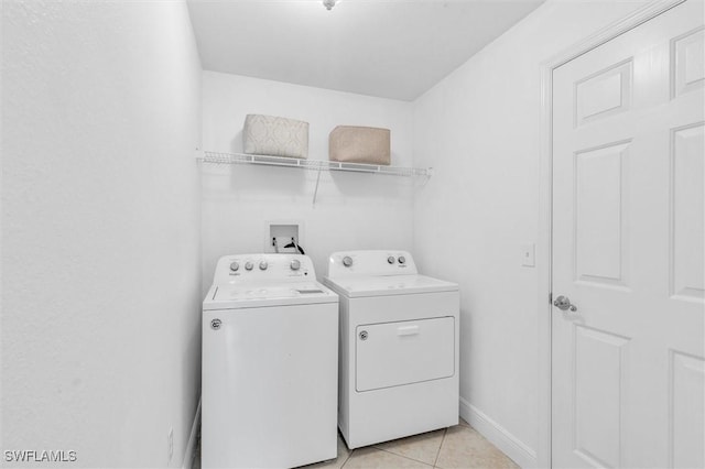 clothes washing area featuring laundry area, baseboards, washer and clothes dryer, and light tile patterned flooring