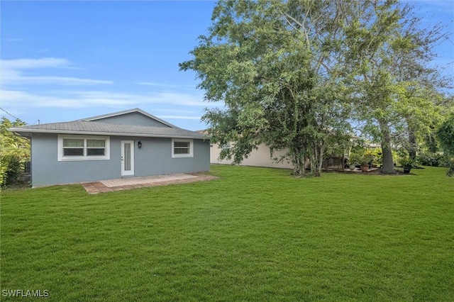 rear view of house with a lawn and stucco siding