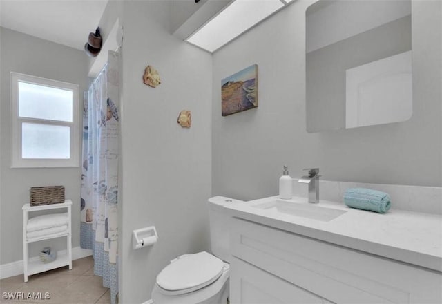 bathroom with toilet, a skylight, vanity, curtained shower, and tile patterned flooring