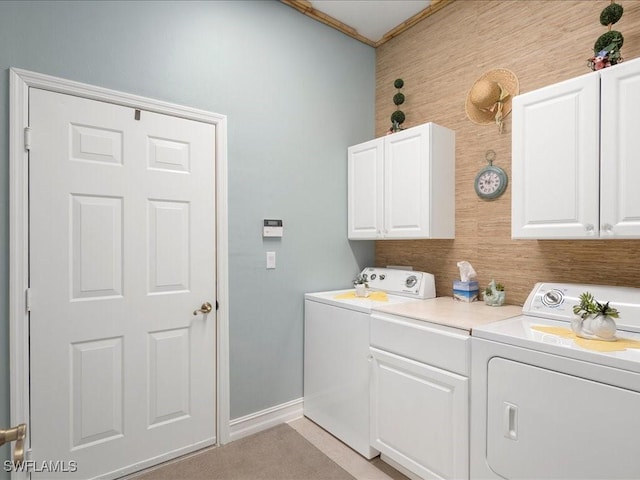 clothes washing area featuring washing machine and dryer, cabinet space, and baseboards