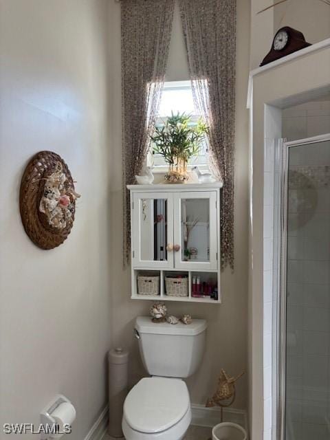 full bath featuring baseboards, a shower stall, and toilet