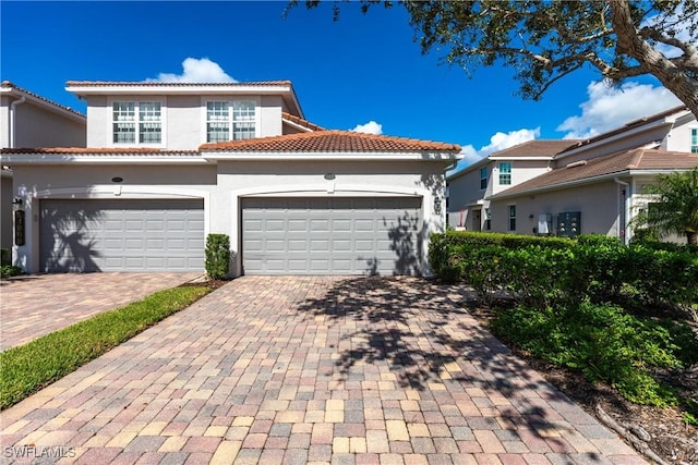 mediterranean / spanish house with a tiled roof, decorative driveway, and stucco siding