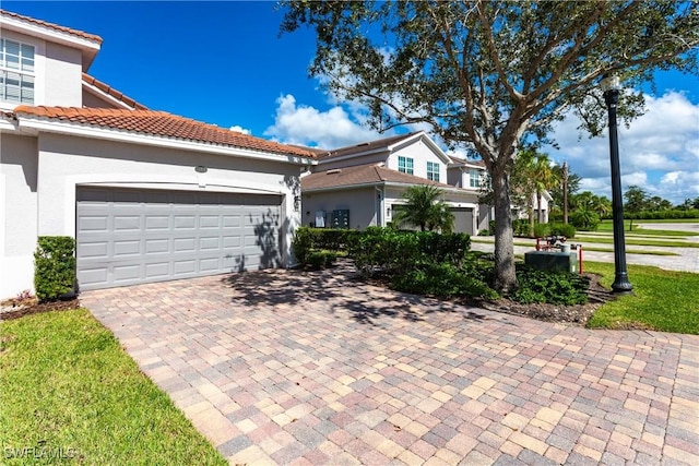 view of front of property with a tiled roof, decorative driveway, an attached garage, and stucco siding