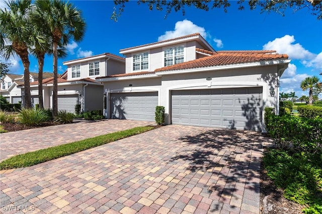 view of front facade with a garage, decorative driveway, a tile roof, and stucco siding