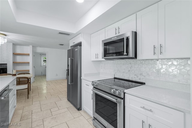 kitchen with stone tile flooring, appliances with stainless steel finishes, light countertops, and a raised ceiling