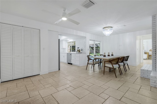 dining space with ceiling fan with notable chandelier, baseboards, visible vents, and stone tile flooring