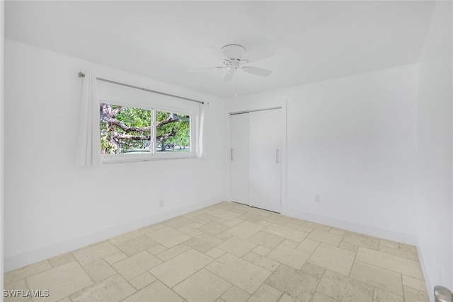 spare room with ceiling fan, baseboards, and stone tile flooring
