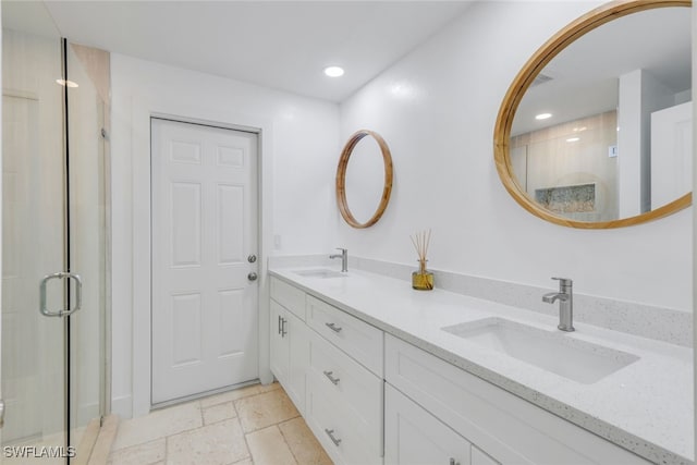 bathroom with a sink, a stall shower, stone tile flooring, and double vanity