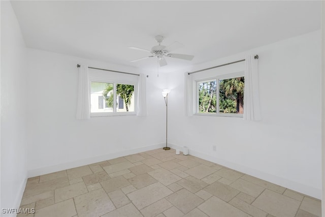 unfurnished room featuring a wealth of natural light, baseboards, and stone tile flooring