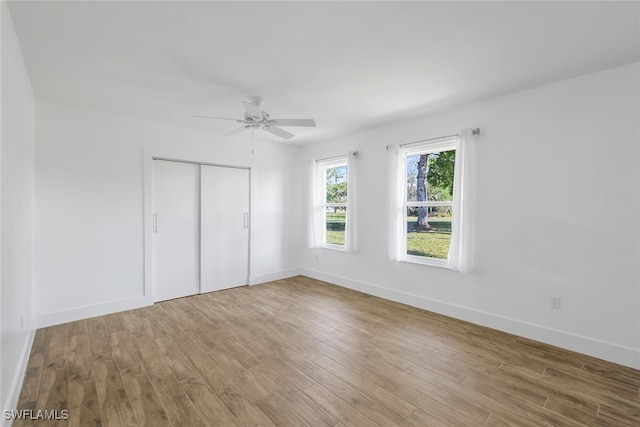 unfurnished bedroom featuring ceiling fan, a closet, baseboards, and wood finished floors