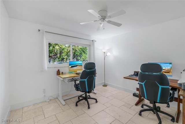 office space featuring a ceiling fan, baseboards, and stone tile flooring