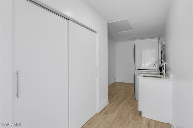 interior space featuring light wood finished floors, attic access, baseboards, and a sink