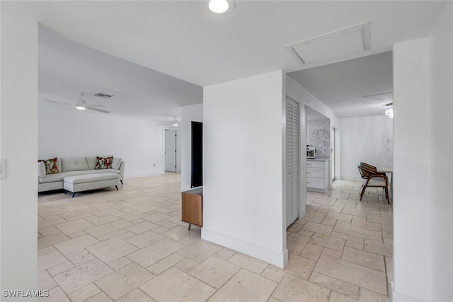 corridor with stone tile floors, visible vents, attic access, and baseboards