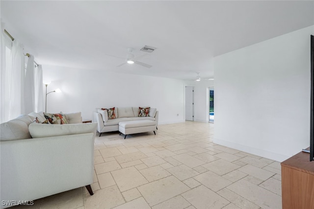 living room with stone tile flooring, visible vents, baseboards, and a ceiling fan