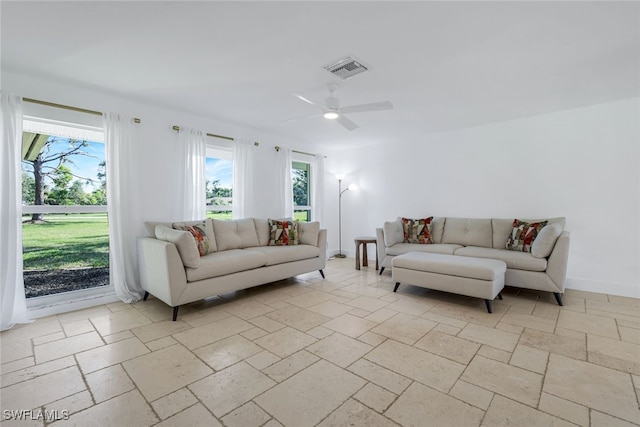 living room with visible vents, baseboards, stone tile flooring, and a ceiling fan