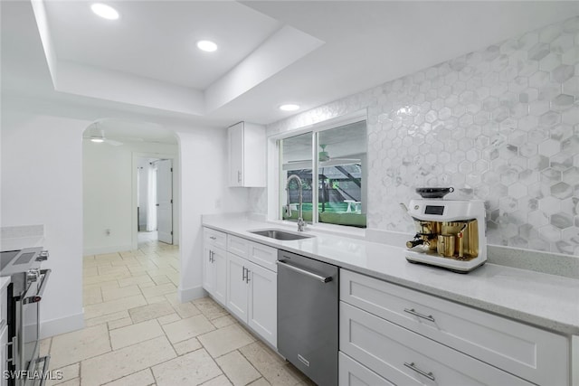 kitchen featuring stainless steel appliances, white cabinets, ceiling fan, a raised ceiling, and sink