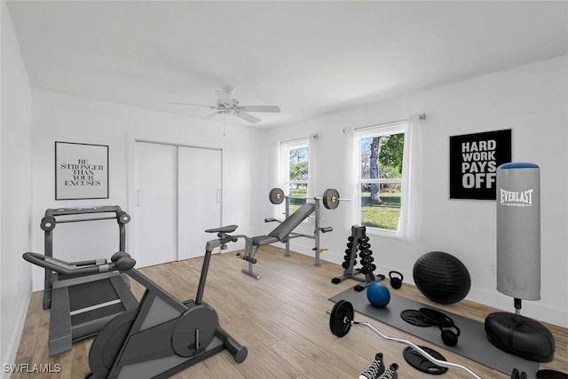 workout area featuring light wood finished floors and baseboards