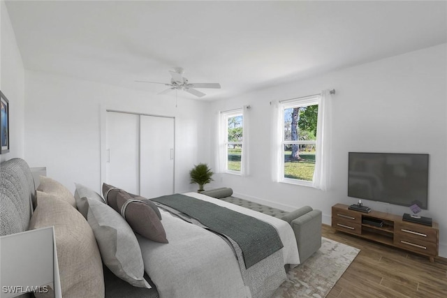 bedroom featuring a ceiling fan, wood finished floors, a closet, and baseboards