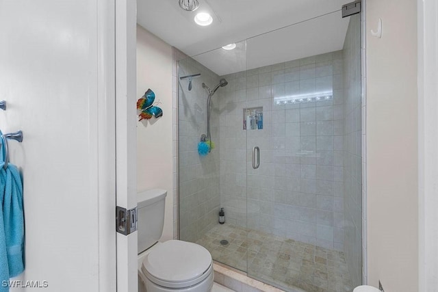 bathroom featuring a shower with shower door and toilet