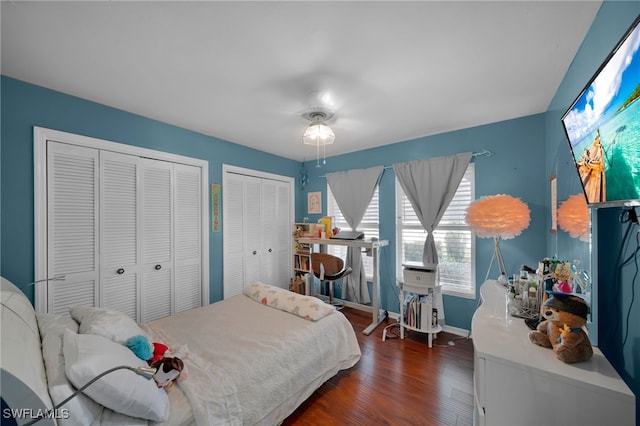 bedroom with multiple closets, dark hardwood / wood-style floors, and ceiling fan