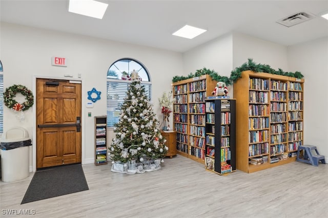 misc room featuring bookshelves, light wood-style flooring, and visible vents