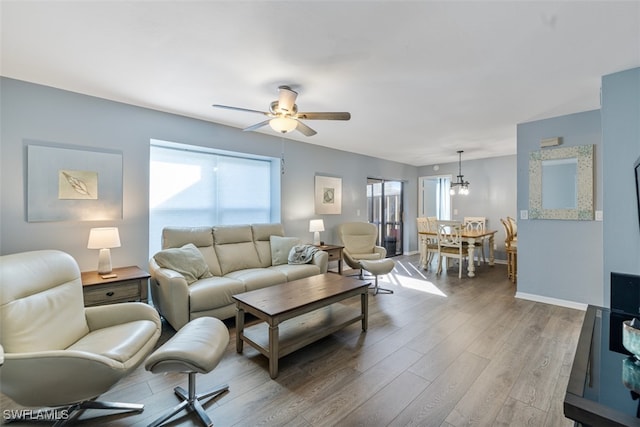 living room featuring a ceiling fan, baseboards, and wood finished floors