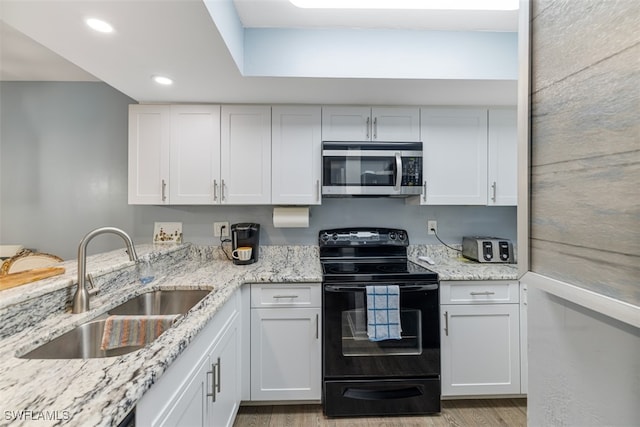 kitchen featuring black electric range, stainless steel microwave, and white cabinetry