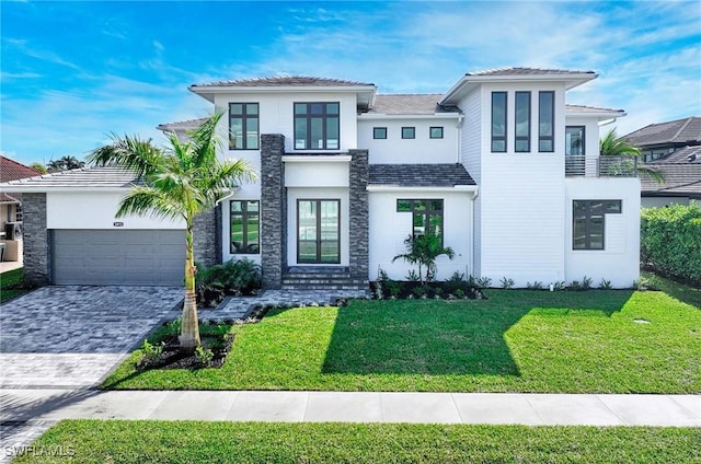 view of front of house with a front yard, decorative driveway, an attached garage, and stucco siding