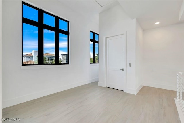 spare room featuring light wood-style floors, recessed lighting, and baseboards