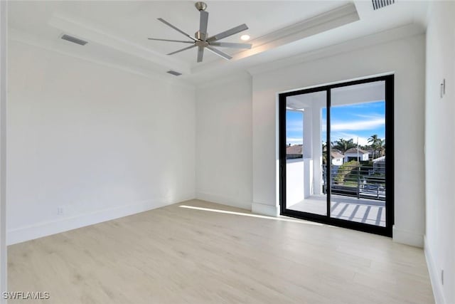 empty room with a tray ceiling, baseboards, and wood finished floors