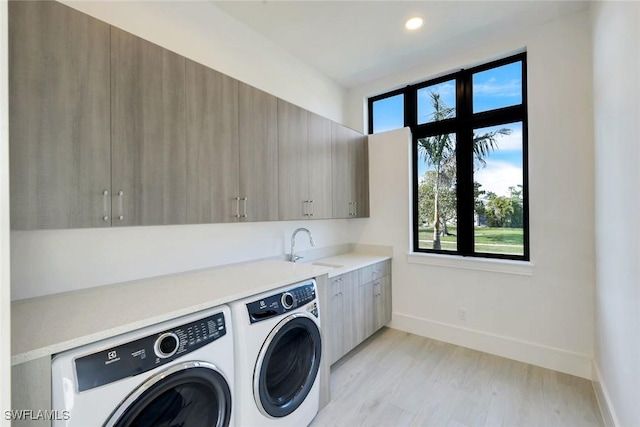 clothes washing area with baseboards, cabinet space, independent washer and dryer, and a sink