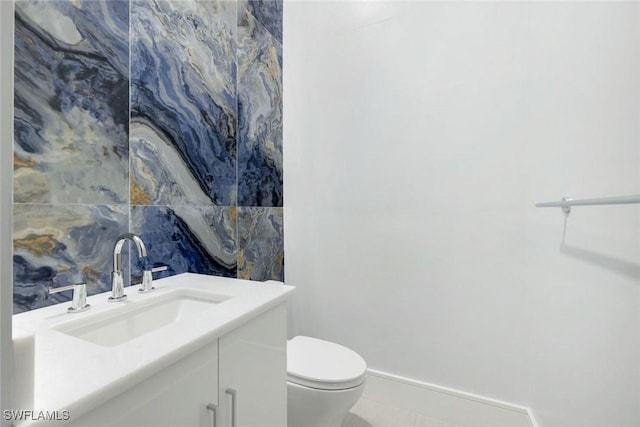 half bathroom featuring tile patterned flooring, baseboards, vanity, and toilet