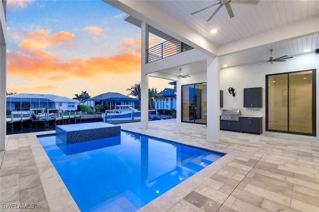 pool at dusk with a grill, a residential view, an outdoor pool, and a ceiling fan