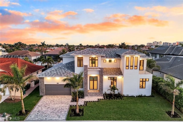 view of front of property featuring a garage, stucco siding, decorative driveway, and a yard