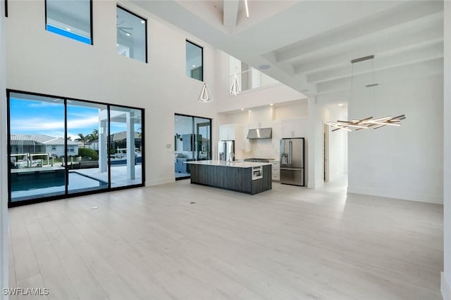 unfurnished living room featuring a sink, ceiling fan, light wood-style flooring, and baseboards