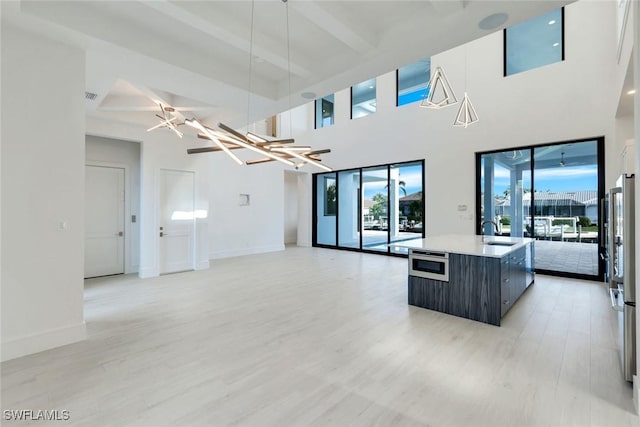 living area featuring a healthy amount of sunlight, light wood-style floors, and beam ceiling