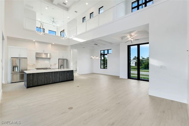 kitchen with ceiling fan, high quality fridge, under cabinet range hood, white cabinetry, and stainless steel refrigerator with ice dispenser