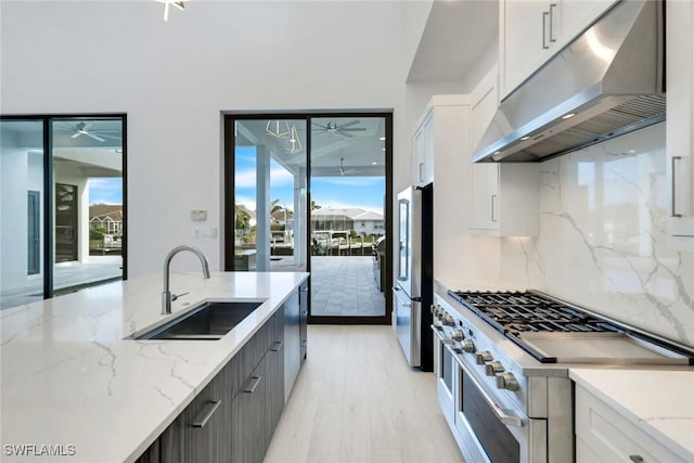 kitchen featuring appliances with stainless steel finishes, backsplash, a sink, under cabinet range hood, and a wealth of natural light